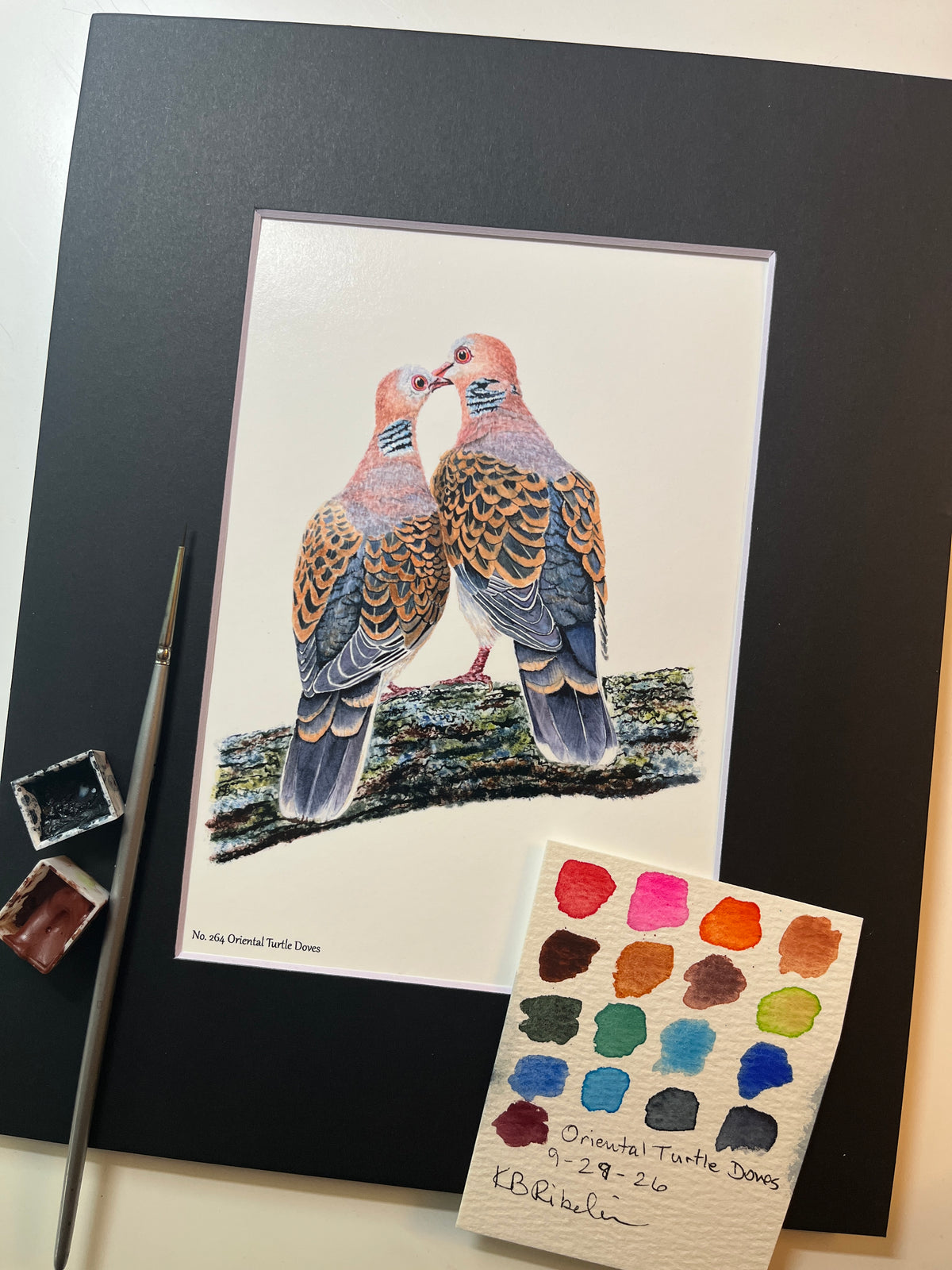 Giclee print of a two oriental turtle doves perched together touching beaks displayed in a black mat.