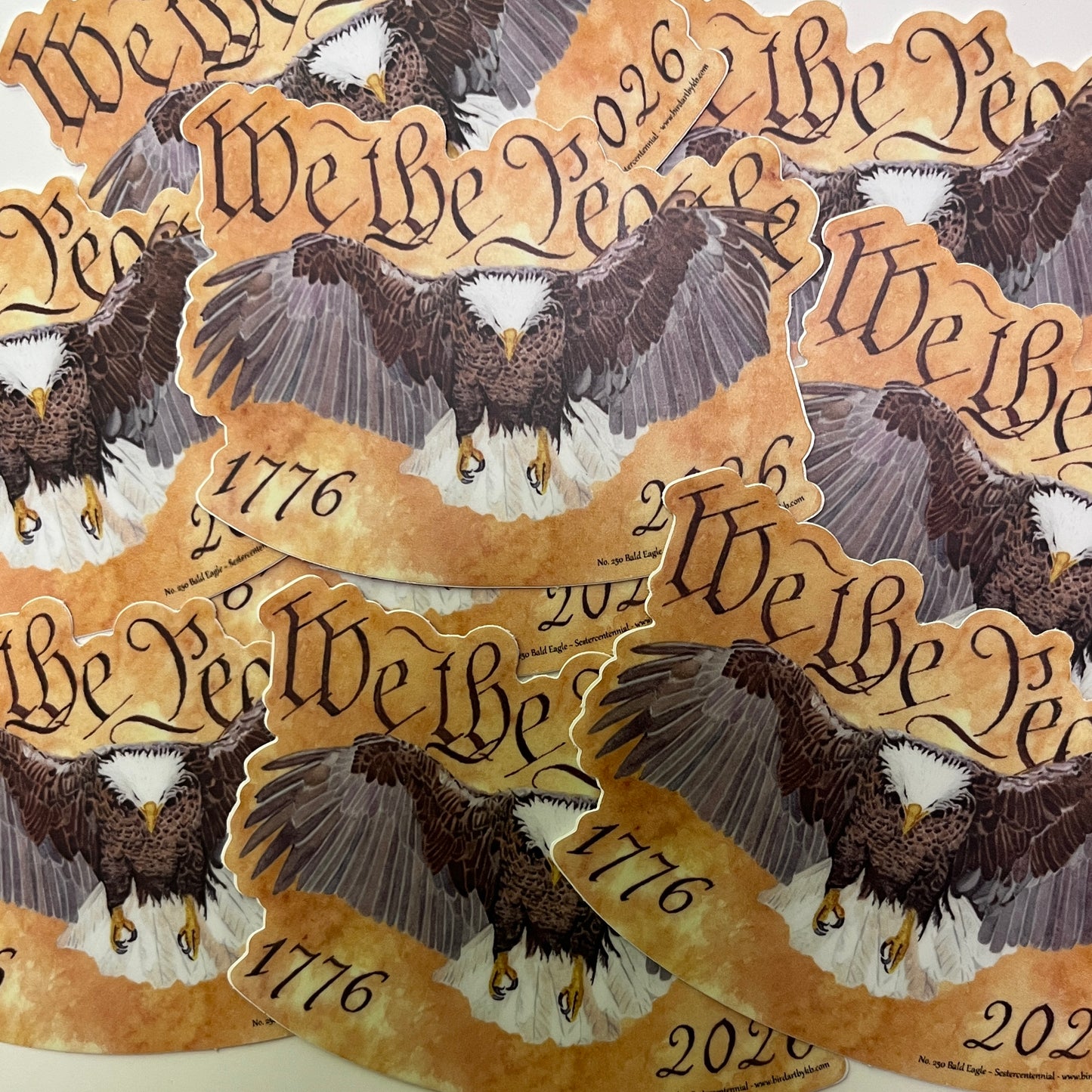 bald eagle flying forward over parchment background with “we the people” lettering