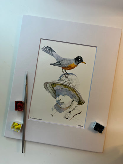 Giclee print of a american robin perched on sculpted girl’s hat displayed in a white mat.
