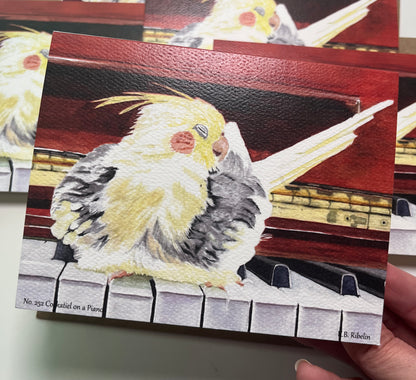 Single notecard printed with the cockatiel perched on a piano painting.