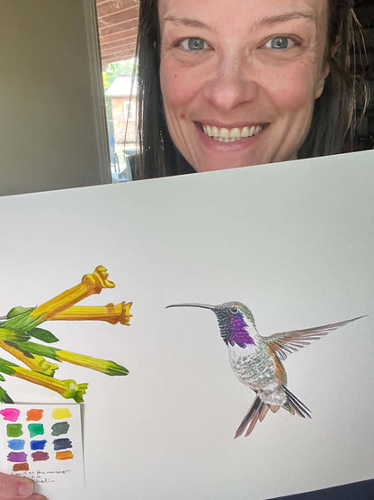 Artist holding the original painting of a lucifer hummingbird hovering near yellow desert flowers, showing the artwork clearly.