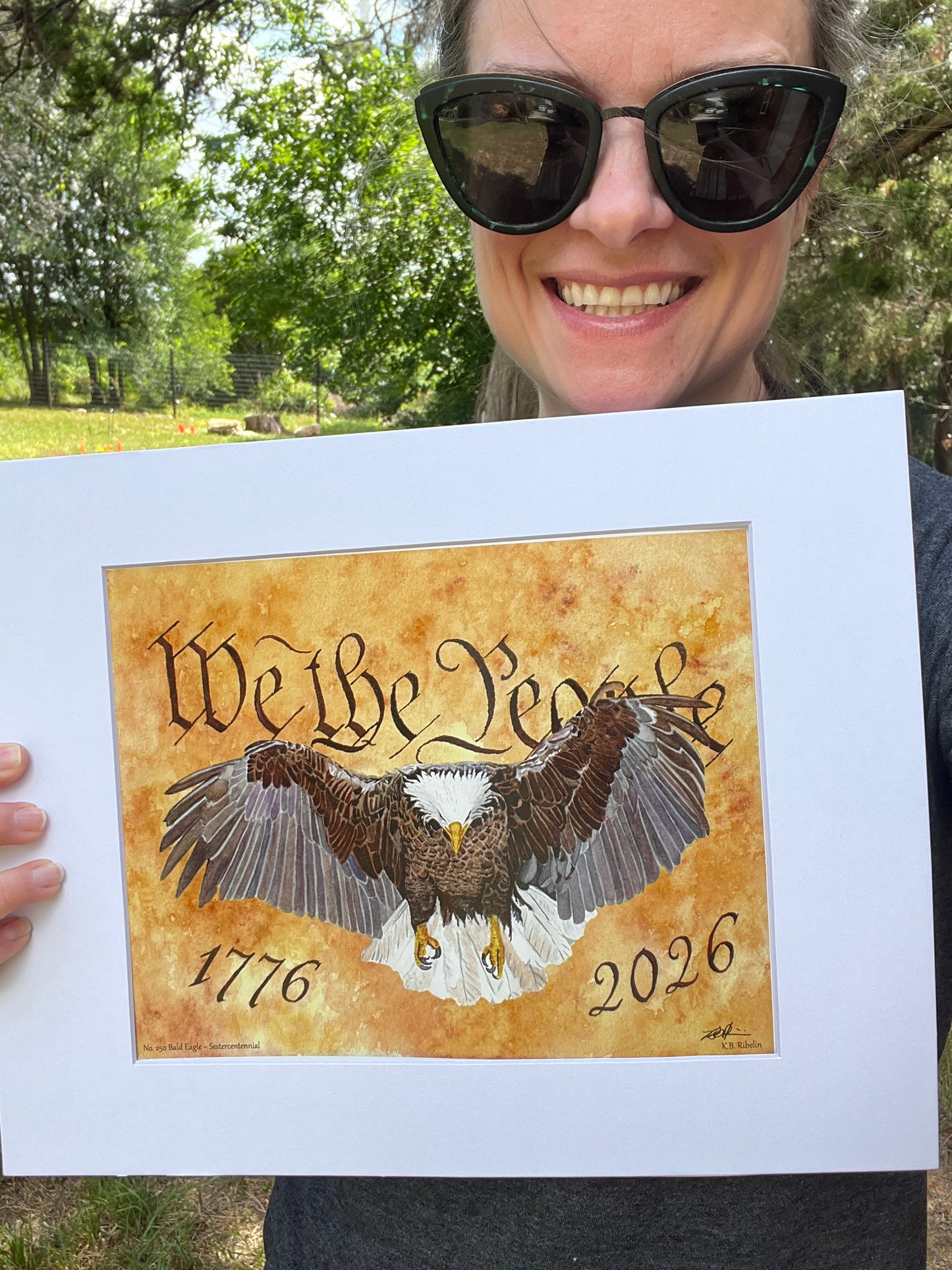 artist holding bald eagle giclee print with “we the people” background