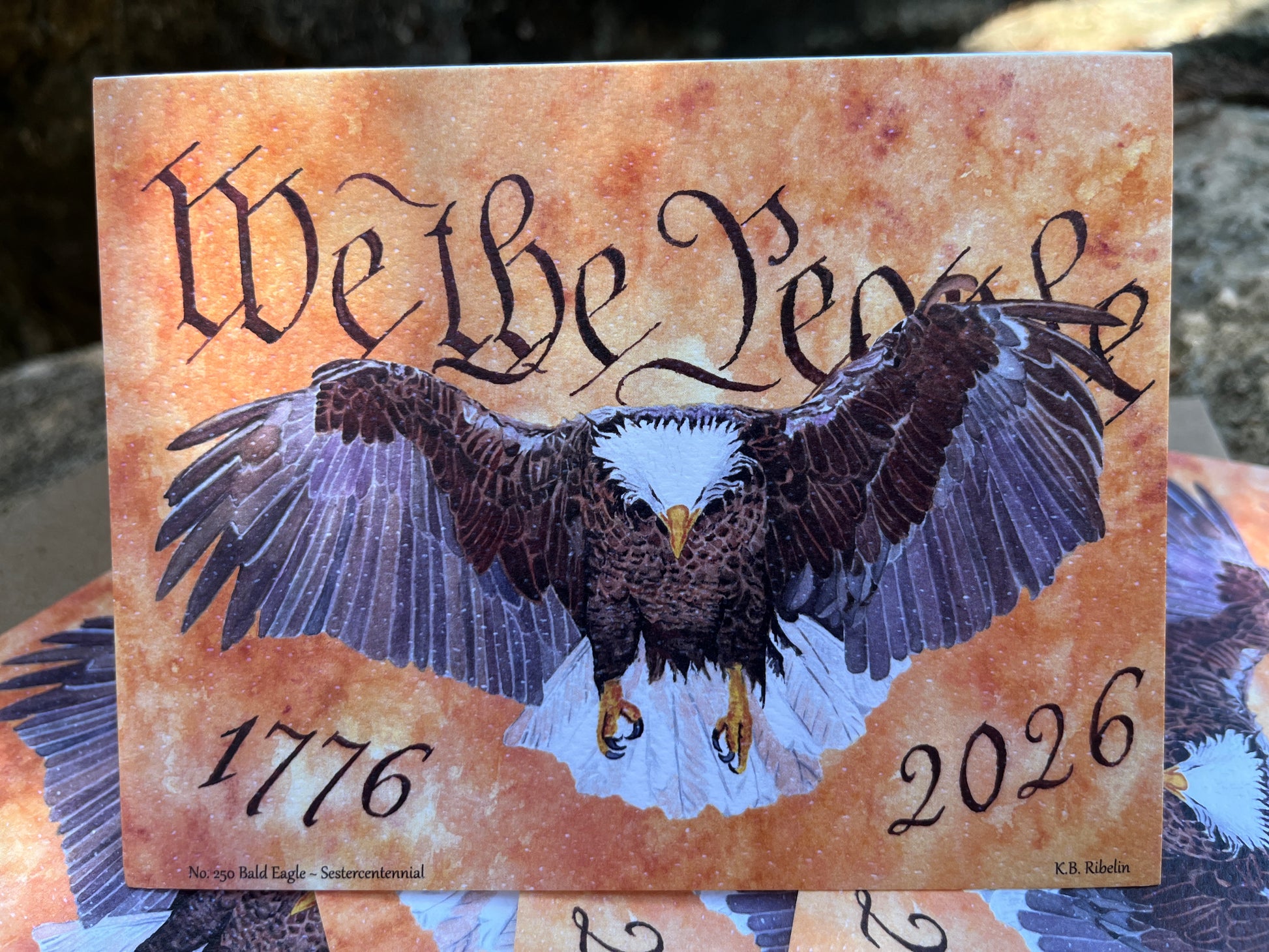 bald eagle flying forward over parchment background with “we the people” lettering