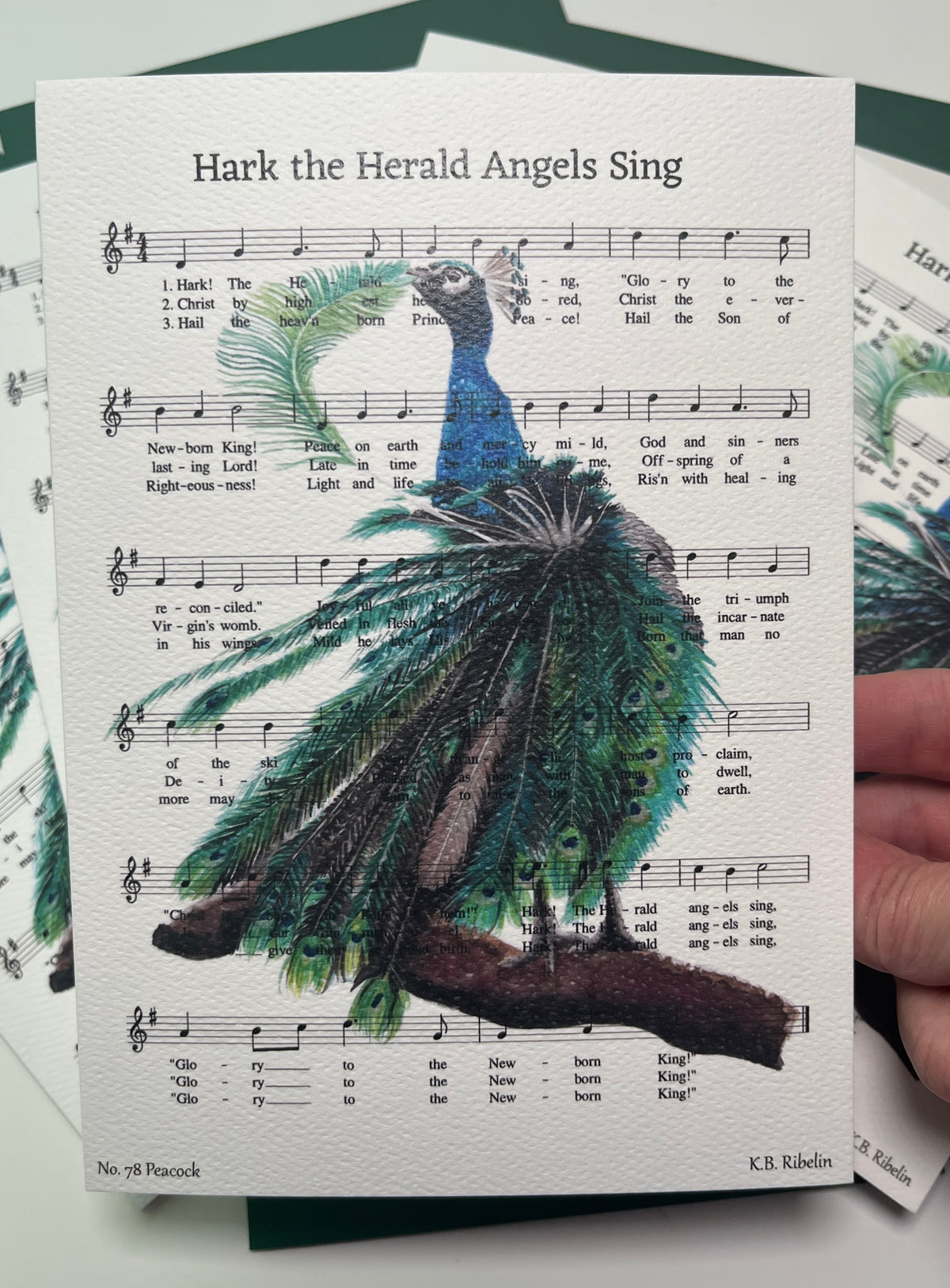 Christmas 2026 notecard featuring Hark the Herald Angels Sing with festive peacock artwork by KB.