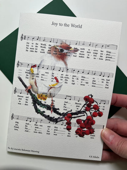 Christmas 2026 notecard featuring Joy to the World with leucistic Bohemian Waxwing artwork by KB.