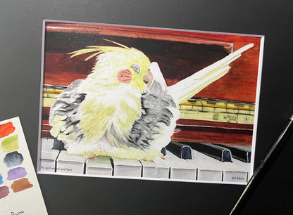 Giclee print of a cockatiel perched on a piano displayed in a black mat.