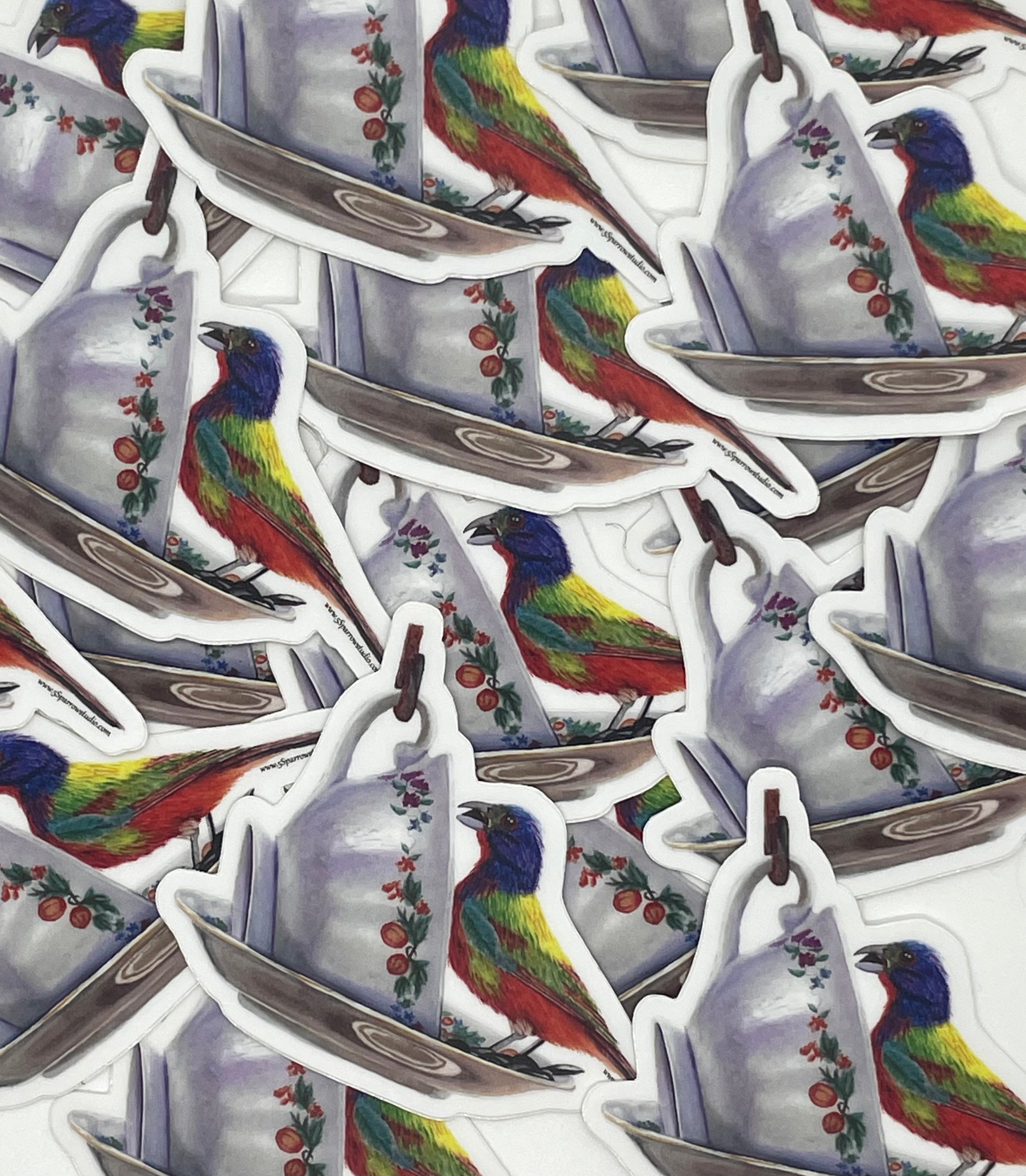 Sticker of the painted bunting perched on a floral teacup artwork.